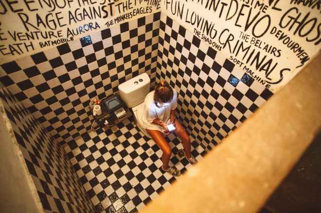 woman sitting on toilet bowl with smartphone